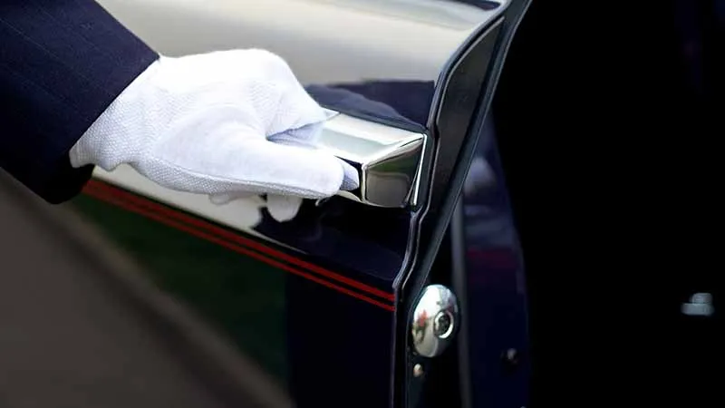 Chauffeur in a white glove opening the door of a limo in Boston